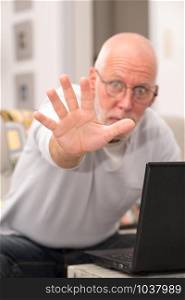 an angry senior man using a laptop in home