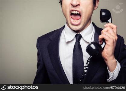 An angry young businesman is on the phone and screaming