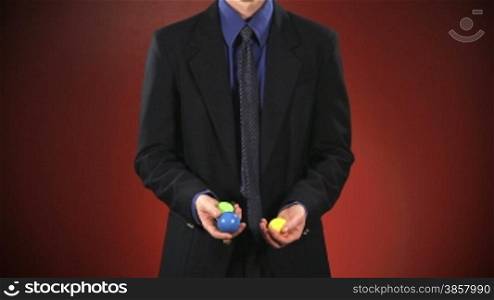 An anonymous businessman in a suit juggles 3 balls in front of a red background. Off-centered version also available.