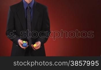 An anonymous businessman in a suit juggles 3 balls in front of a red background. Centered version also available.