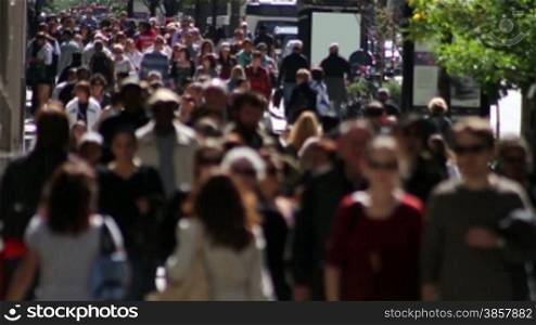 An anonymous crowd walking on a city sidewalk in fast motion