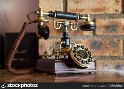 An antique analog telephone set with black box base and golden ringer, and handset