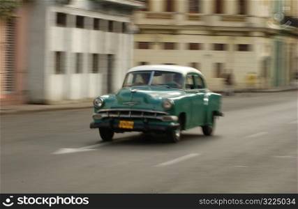 An antique car moving on a road, Havana, Cuba