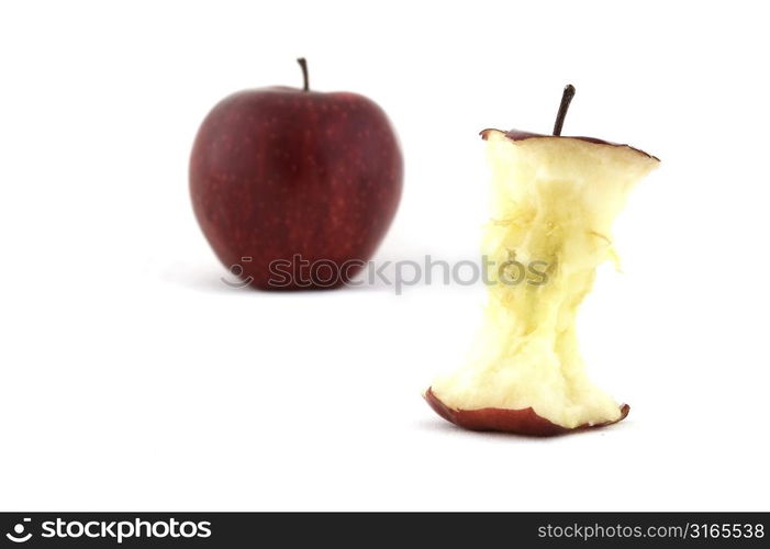 An apple core with an apple in the background