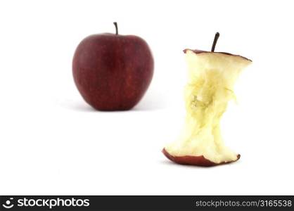 An apple core with an apple in the background