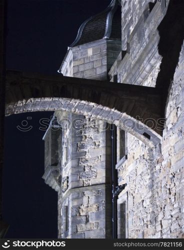 An arch connecting two buildings of the main citadel in Edinburgh Castle. At night, the wall on the left dissolves into the evening sky and the shadows become dramatic.