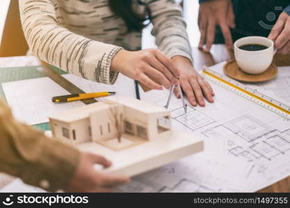 An architect using compass to draw and measure shop drawing in office