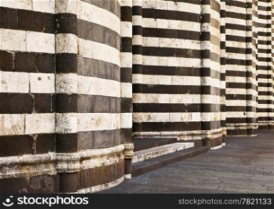 An architectural detail view of the alternating pattern of black and white stone layers used as the exterior facade of the main cathedral, or Duomo, in Orvieto, Italy.