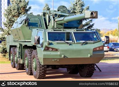 An army military vehicle with artillery anti-aircraft gun and guided missiles on board is parked in a car park on a bright summer day.. Self-propelled artillery is parked in the parking lot.