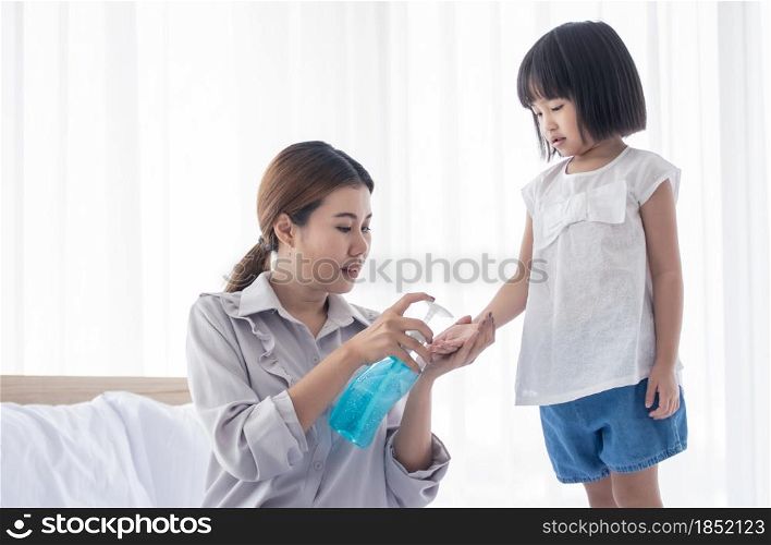 An asian beautiful mother washing her daughter&rsquo;s hand by alcohol gel to prevent virus