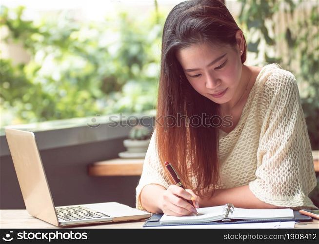 An asian beautiful woman is using laptop and mobile phone for planning jobs and working at home