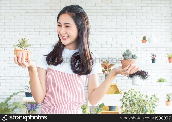 An asian beautiful woman smiling with happiness while gardening and holding plants as her hobby at home
