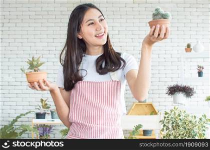 An asian beautiful woman smiling with happiness while gardening and holding plants as her hobby at home