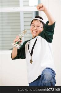 An asian boy excited aboyt his winning sport medal and trophy