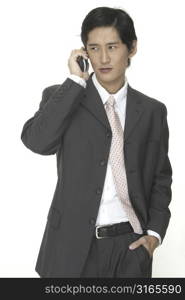 an asian businessman in a grey suit talks on a cordless phone