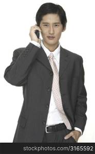 an asian businessman in a grey suit talks on the phone