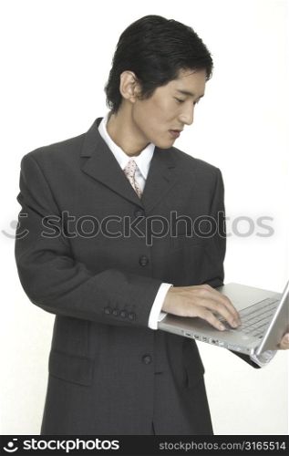 an asian businessman keeps up to date using his laptop computer