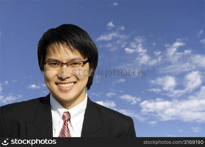 An asian businessman posing outdoor against blue sky