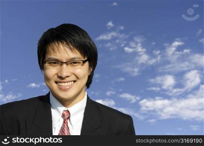 An asian businessman posing outdoor against blue sky