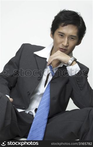 an asian businessman sits and stares into space