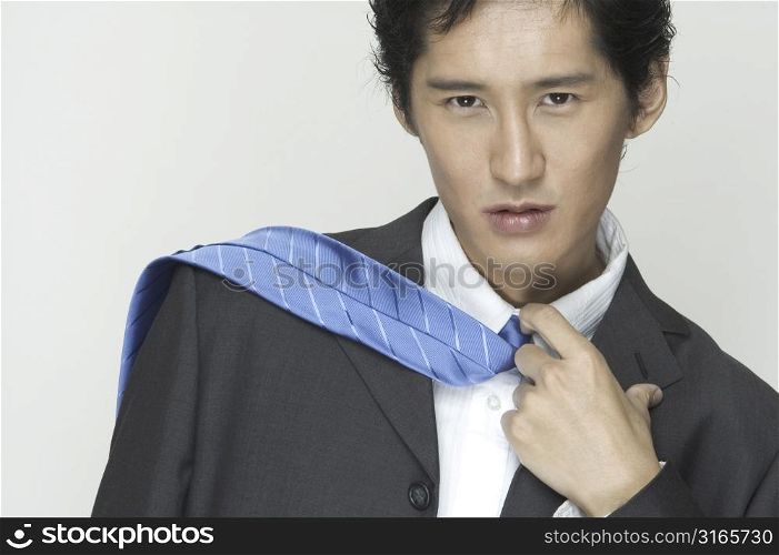An asian businessman with tie flicked across shoulder