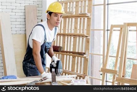 An asian carpenter using drill machine to make a hold on wood