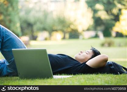 An asian college student lying down on the grass
