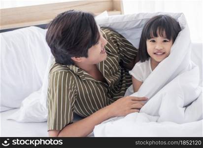 An Asian dad and little daughter are playing together on bedroom at home