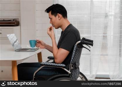 An Asian disabled man sits in a wheelchair is stressed and disappointed And taking medicine After having a car accident, The concept of negligence and the effects of drunk driving.
