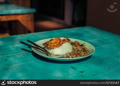 An asian dish on a blue table in a restaurant in the sunlight