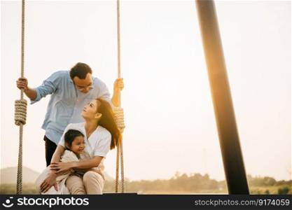 An Asian family having fun in the garden, with the father and daughter swinging on a sunny spring day, feeling the happiness and the love of a playful family, Happy Family Day