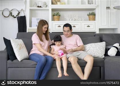 An asian family is teaching daughter on savings money with a piggy bank, financial planning concept