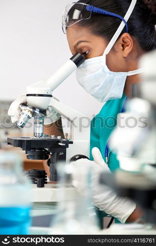 An Asian female medical doctor or scientific researcher using her microscope in a laboratory.