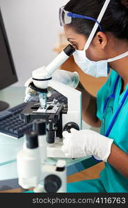 An Asian female medical doctor or scientific researcher using her microscope in a laboratory.