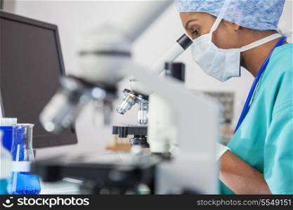 An Asian female medical doctor or scientific researcher using her microscope in a laboratory.