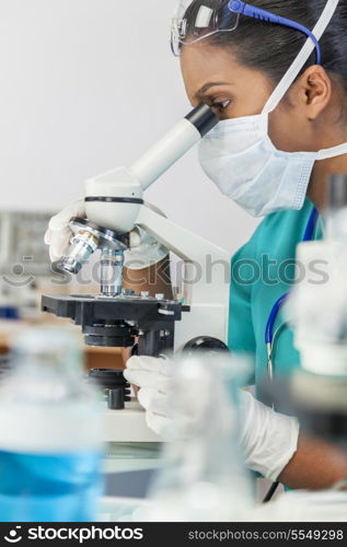 An Asian female medical doctor or scientific researcher using her microscope in a laboratory.