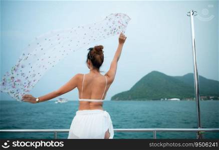 An Asian girl on a yacht stand to receive the fresh air from the sea with a shawl that flew in beautiful waves
