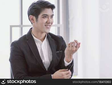 An asian handsome business man is dressing up and fixing cufflink