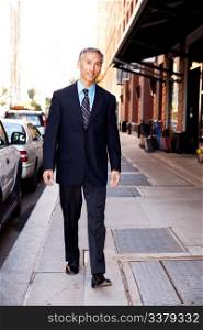 An asian looking business man walking in a street