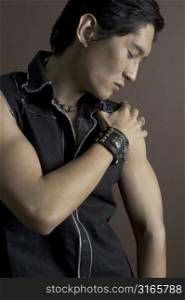 An asian male model in a black top and studded bracelet