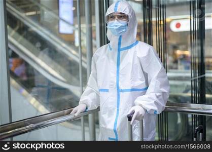 An Asian man is wearing ppe suit in airport elevator , Safety travel , covid-19 protection , social distancing concept .. An Asian man is wearing ppe suit in airport elevator , Safety travel , covid-19 protection , social distancing concept