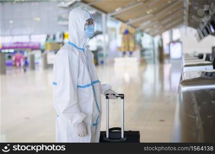 An Asian man is wearing ppe suit in International airport , Safety travel , covid-19 protection , social distancing concept .. An Asian man is wearing ppe suit in International airport , Safety travel , covid-19 protection , social distancing concept
