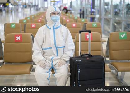 An Asian man is wearing ppe suit in International airport , Safety travel , covid-19 protection , social distancing concept .. An Asian man is wearing ppe suit in International airport , Safety travel , covid-19 protection , social distancing concept