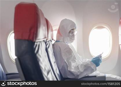 An Asian man is wearing protective suit , PPE suit in airplane , safety travel concept .