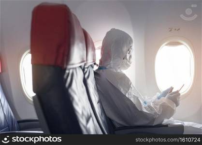 An Asian man is wearing protective suit , PPE suit in airplane , safety travel concept .