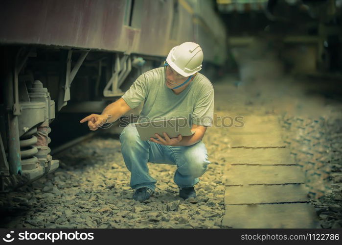 an asian railroad engineer checking a train