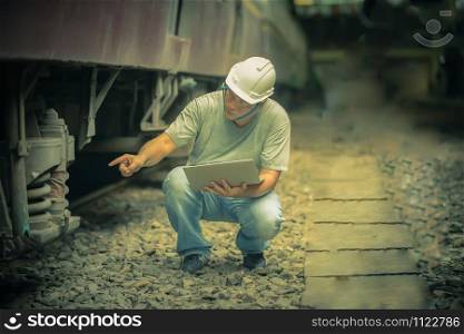 an asian railroad engineer checking a train