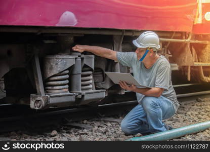 An asian railroad engineer checking a train