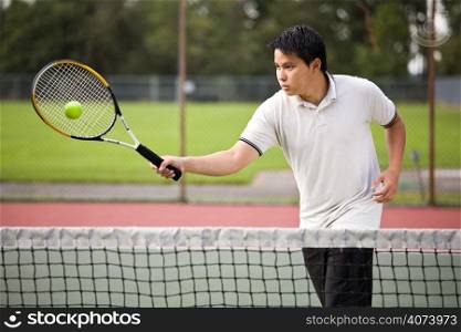 An asian tennis player hitting the ball