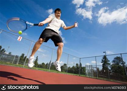 An asian tennis player jumping in the air hitting a tennis ball